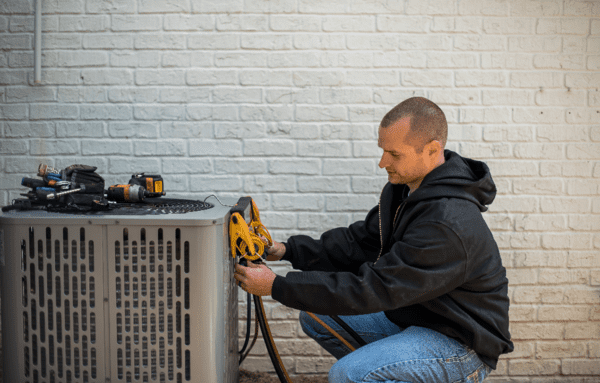 HVAC-maintenance-technician-placing-gauges-on-ac-unit