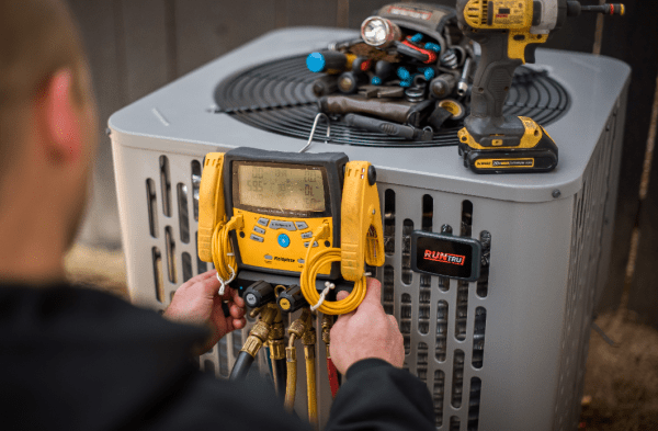 HVAC-maintenance-technician-adjusting-gauges-on-ac-unit