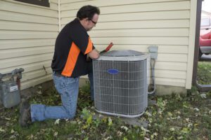 Repairman Checking Outside Air Conditioning Unit For Voltage HVAC-Maintenance-Technician