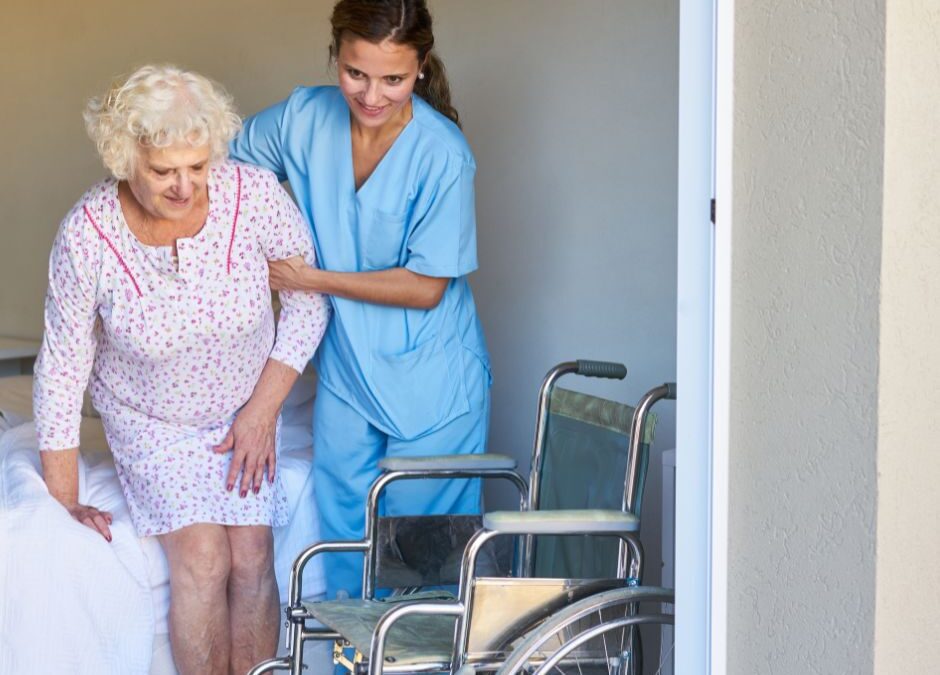 older-female-being-helped-into-wheelchair-by-caregiver