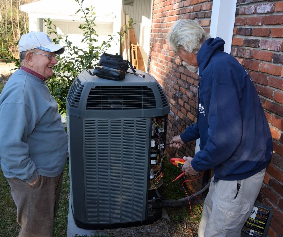 HVAC-Technician-Talking-with-Happy-Customer-While-Working-on-Heat-Pump