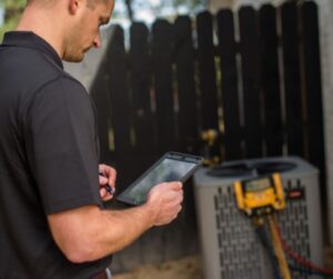 Heating-and-Air-Technician-Looking-at-iPad-and-Working-on-HVAC-System