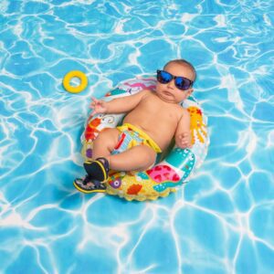 Young-Baby-with-Sunglasses-and-Flip-Flops-Sitting-in-Float-in-Pool